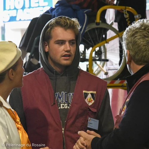Jeune bénévole Pèlerinage du Rosaire en discussion.