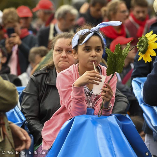 Jeune fille participant au Pèlerinage du Rosaire, buvant un verre.