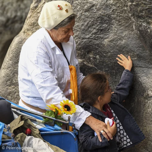 Femme et enfant touchant un rocher, Pèlerinage du Rosaire