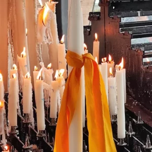 Bougies blanches allumées avec ruban jaune dans une église
