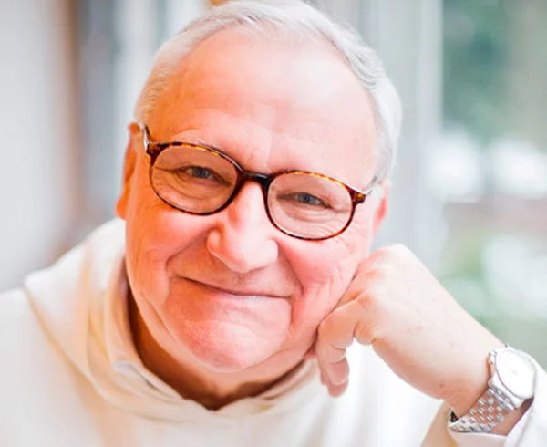 Portrait d'un homme âgé souriant avec des lunettes.