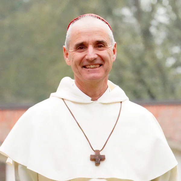 Moine souriant portant un habit religieux et une croix.