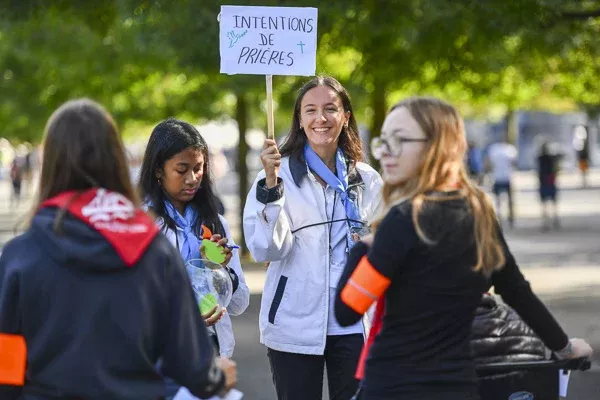 Jeunes collectant intentions de prières avec pancarte