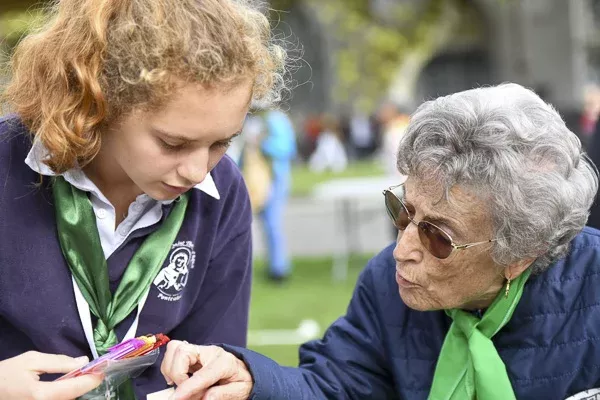 Jeune scout aidant une dame âgée à choisir couleurs