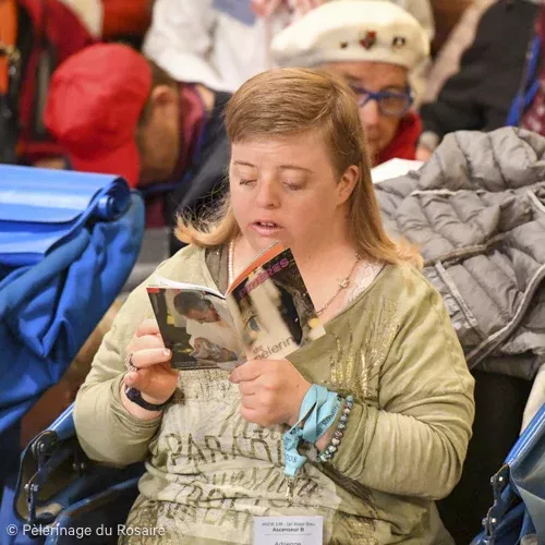 Femme lit publication pendant le pèlerinage du Rosaire